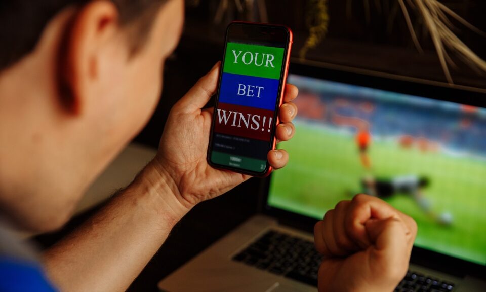 Man being happy winning a bet in online sport gambling application on his mobile phone